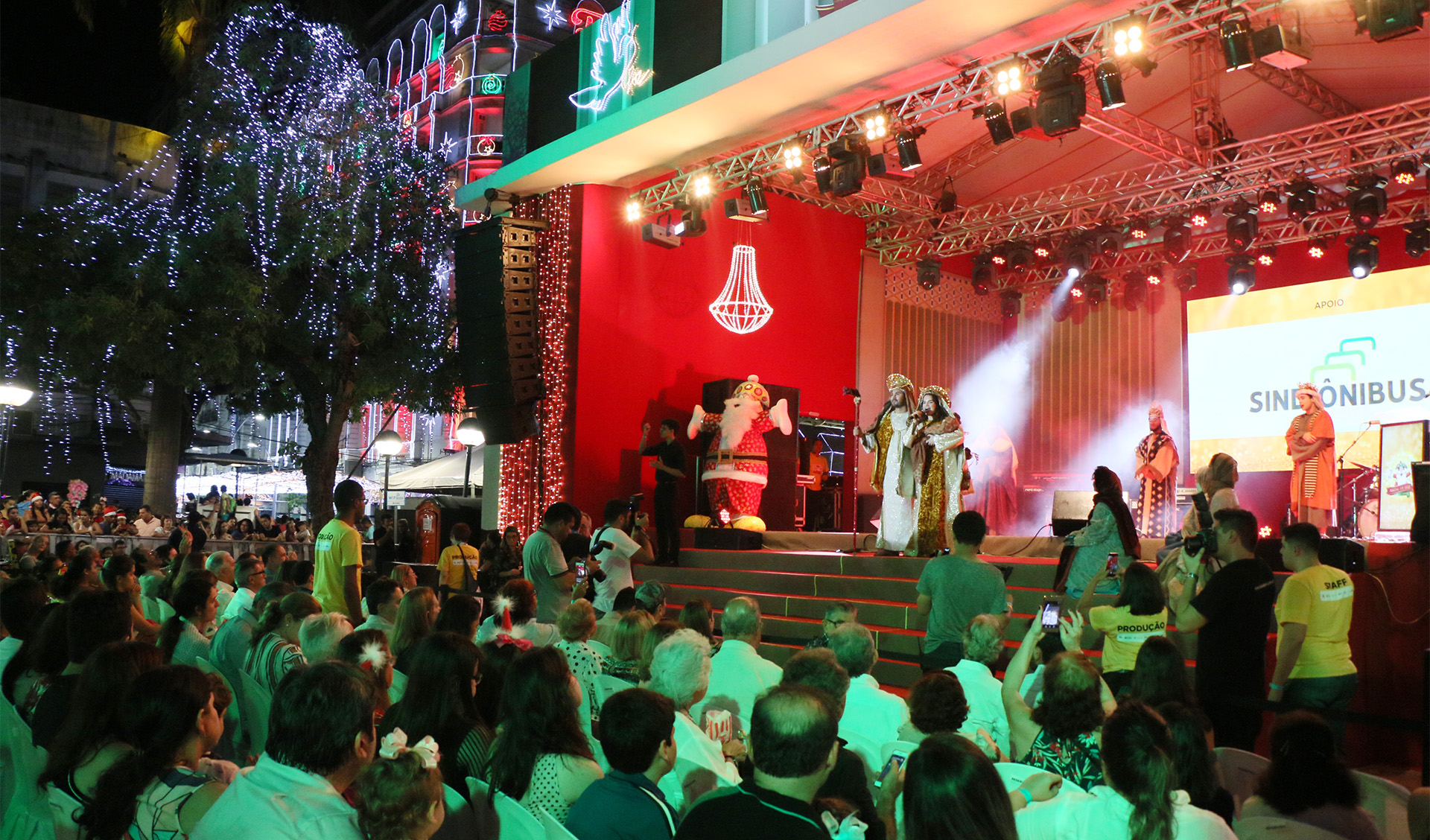 Palco do natal de luz, com atores interpretando Maria, José e o menino Jesus